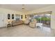 Comfortable living room features tile floors, a ceiling fan, and sliding glass door to screened lanai at 1474 Red Oak Ln, Port Charlotte, FL 33948