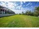 Expansive backyard with lush green grass, a screened-in patio, and tropical landscaping at 16531 San Edmundo Rd, Punta Gorda, FL 33955