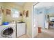 Light and airy laundry room with modern washer and dryer units, vintage decor, and access to bathroom at 16531 San Edmundo Rd, Punta Gorda, FL 33955