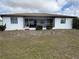 Rear exterior view of home with screened in back porch, and well maintained yard at 18422 Arapahoe Cir, Port Charlotte, FL 33948