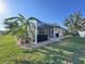 Backyard featuring screened patio, lush green grass, and surrounding tropical foliage at 1859 Scarlett Ave, North Port, FL 34289