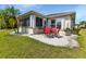 The backyard features a patio area with red chairs, and green grass at 1944 Boddington Trl, Port Charlotte, FL 33980