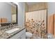 Bathroom featuring granite countertop, tiled shower, and decorative floral shower curtain at 206 Santarem Cir, Punta Gorda, FL 33983