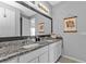 Bathroom featuring double sinks, granite counters, decorative wall hangings, and a large framed mirror at 206 Santarem Cir, Punta Gorda, FL 33983