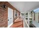 Second-story exterior hallway with brick walls, white trim, and secure, numbered entry doors at 380 Base E Ave # 202, Venice, FL 34285
