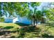 Exterior view showcasing the blue home and detached garage, complemented by lush landscaping and palm trees at 434 W Grace St, Punta Gorda, FL 33950