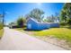 Exterior view of blue detached garage/outbuilding with a white door surrounded by lush green grass and clear blue skies at 434 W Grace St, Punta Gorda, FL 33950