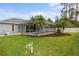 A backyard featuring a screened-in pool area, palm trees, and manicured lawn for outdoor relaxation at 4571 La Rosa Ave, North Port, FL 34286