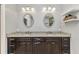 Bathroom featuring a granite counter, dark cabinets and dual oval shaped mirrors at 5601 Taylor Rd, Punta Gorda, FL 33950
