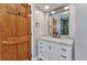 Bathroom vanity with a marble countertop, white cabinets, black hardware, and a framed mirror at 5601 Taylor Rd, Punta Gorda, FL 33950