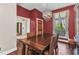 Formal dining room with elegant chandelier, wood floors, and red accent wall at 5601 Taylor Rd, Punta Gorda, FL 33950