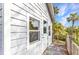 Side exterior view of a charming structure with white siding and a wooden deck, nestled in lush greenery at 5601 Taylor Rd, Punta Gorda, FL 33950