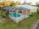Aerial view of a home featuring a screened-in pool area, set amidst lush landscaping and mature trees at 6938 Rabbit Ave, North Port, FL 34291