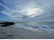 Serene beach scene with gentle waves, a rocky breakwater and a cloudy sky at 7243 Patricia Pl, Englewood, FL 34224