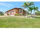 Exterior side view of a single-Gathering home featuring a manicured lawn and mature palm trees at 10393 Harlingen St, Port Charlotte, FL 33981