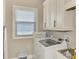 Bright laundry room with white cabinetry, modern washer and dryer, and utility sink at 10393 Harlingen St, Port Charlotte, FL 33981
