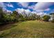 Expansive backyard with lush green grass, mature trees, and a screened-in porch offers a private retreat at 1169 Presque Isle Dr, Port Charlotte, FL 33952