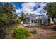 View of the backyard with screened-in pool and surrounding tropical landscaping on a sunny day at 1169 Presque Isle Dr, Port Charlotte, FL 33952