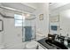 Bright bathroom with a shower-tub combo featuring sliding glass doors and a black countertop sink at 1169 Presque Isle Dr, Port Charlotte, FL 33952