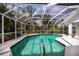 Screened-in pool with clear water and white trim, surrounded by lush trees and foliage at 1169 Presque Isle Dr, Port Charlotte, FL 33952