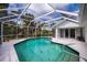 Screened-in pool with clear water, surrounded by a white patio and lush landscaping at 1169 Presque Isle Dr, Port Charlotte, FL 33952