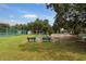 Outdoor shuffleboard courts with benches and a nearby tennis court, set amongst mature trees at 1350 Old Oak Trl, Port Charlotte, FL 33948