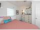 Inviting bedroom with a soft pink comforter, a white dresser, a decorative mirror, and ample lighting at 137 Poinsettia Ne Cir, Port Charlotte, FL 33952