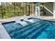 Inviting in-pool seating is featured in this screened-in pool area with a nearby outdoor shower at 14029 Cain Ave, Port Charlotte, FL 33953