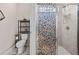 Bathroom showcasing shower with decorative glass door, toilet, and shelving unit at 1470 Atwater Dr, North Port, FL 34288