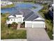 Aerial shot of a beautiful one-story home with lake view, a black roof, an oversized driveway and attached two-car garage at 15155 Scarlet Oak Ct, Punta Gorda, FL 33955
