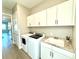 Bright laundry room featuring white cabinets, granite countertop, sink, washer, and dryer at 15155 Scarlet Oak Ct, Punta Gorda, FL 33955