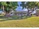 A view of the home's backyard and patio, with mature shade trees, lawn, and partial view of the canal at 2501 Rio Grande Dr, Punta Gorda, FL 33950