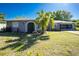 Charming single-story home featuring a well-manicured lawn, mature palm tree, and neutral toned facade under a bright blue sky at 2550 Ivanhoe St, Port Charlotte, FL 33952