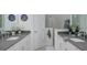 Bathroom with double sinks, gray countertops, tiled floors and a shower with a glass door and tiled walls at 27500 Janzen Ct, Englewood, FL 34223