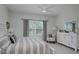 Bright bedroom featuring a ceiling fan, window, white furniture, and a beautifully made queen size bed with gray accents at 27500 Janzen Ct, Englewood, FL 34223