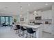 Open-concept kitchen with white cabinetry, stainless steel appliances, pendant lighting and an island with bar seating at 27500 Janzen Ct, Englewood, FL 34223