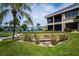 Scenic view of the building's exterior featuring a bridge, tropical landscaping, and a glimpse of the tennis court at 3256 White Ibis Ct # 13B, Punta Gorda, FL 33950