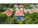Lovely aerial view of a screened in swimming pool surrounded by lush landscaping and terracotta tiled roofs at 5017 Hanging Moss Ln, Sarasota, FL 34238