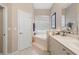 Bright bathroom featuring a soaking tub with tile surround, vanity, and neutral color palette at 5017 Hanging Moss Ln, Sarasota, FL 34238