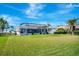 Backyard view showing mature palm trees, green grass and screened lanai at 507 Monaco Dr, Punta Gorda, FL 33950
