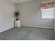 A clean, carpeted bedroom has a window and an empty corner awaiting a personal touch at 507 Monaco Dr, Punta Gorda, FL 33950