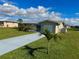 Single-story home with neutral paint, an attached garage, a palm tree in the front yard, and a concrete driveway at 61 Caddy Rd, Rotonda West, FL 33947