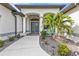 Elegant front entrance featuring a covered doorway, well-kept garden beds, and blue Adirondack chairs at 664 Rotonda Cir, Rotonda West, FL 33947
