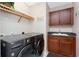 Modern laundry room with front-loading washer and dryer, cabinets, sink, and wooden shelf at 87 Vivante Blvd # 8732, Punta Gorda, FL 33950