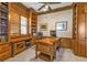 Elegant home office boasts custom wood built-ins, a ceiling fan, and natural light from window with plantation shutters at 12905 N Marsh Dr, Port Charlotte, FL 33953