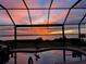 Screened-in lanai with pool overlooks the water at sunset at 12905 N Marsh Dr, Port Charlotte, FL 33953
