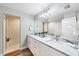Bright bathroom featuring dual sinks, marble countertops, a large mirror, and walk-in shower with tile surround at 14325 Mcfarland Ave, Port Charlotte, FL 33981