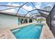 Enclosed pool and spa area with brick patio, a view of the lanai and surrounding landscaping at 14325 Mcfarland Ave, Port Charlotte, FL 33981