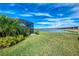 Beautiful backyard featuring lush greenery, a screened-in lanai, and a tranquil lake view at 15033 Spanish Point Dr, Port Charlotte, FL 33981