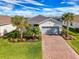 Charming single-story home featuring a brick driveway, well-kept lawn and beautiful tropical landscaping at 15033 Spanish Point Dr, Port Charlotte, FL 33981